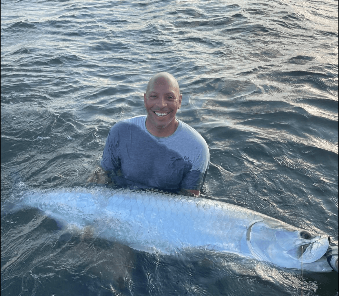 A man is holding a large fish in the water.