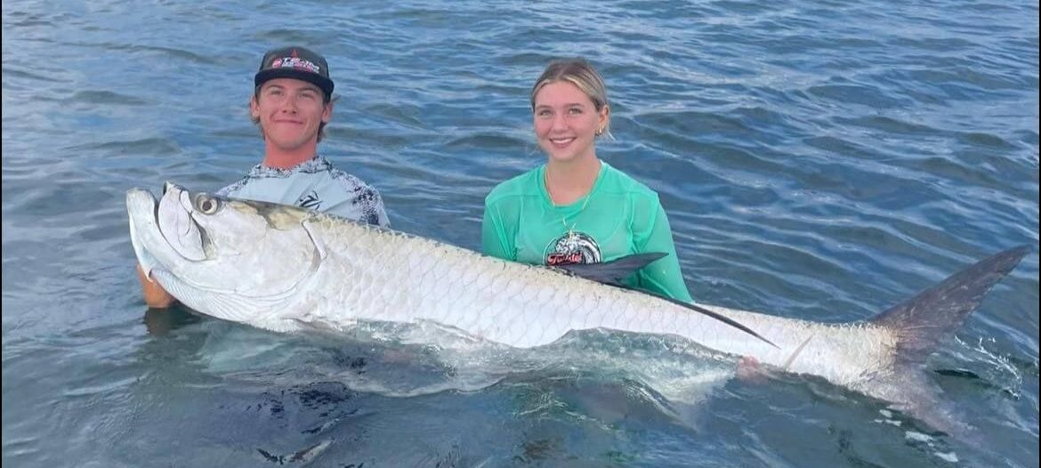 Captain Jake Wise tarpon fishing and holding a catch.