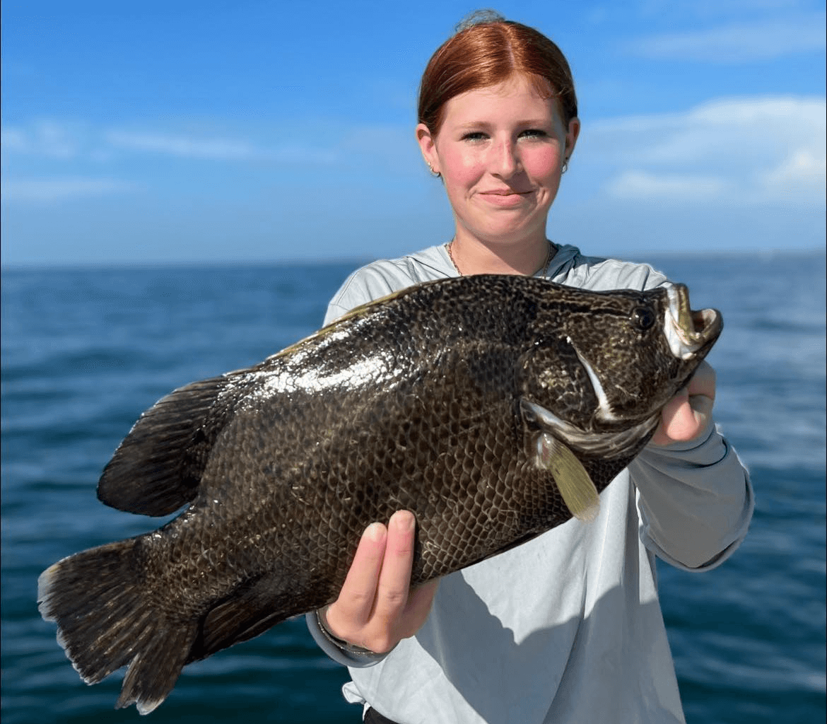 A woman is holding a large fish in her hands.