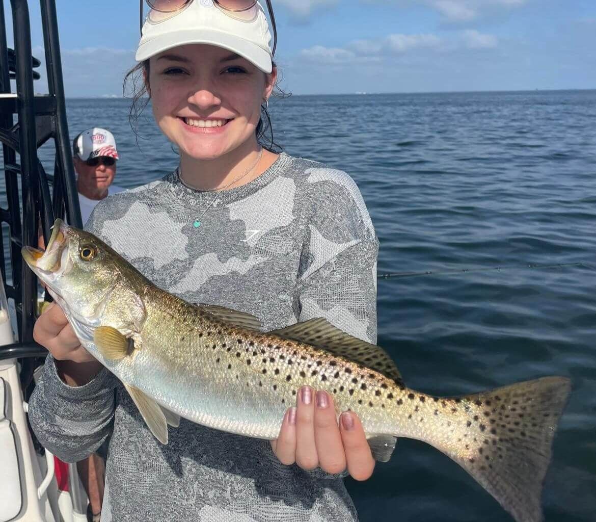 A woman is holding a fish in her hands on a boat.