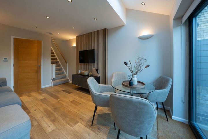 A living room with a dining table and chairs and a flat screen tv.