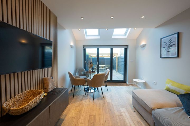 A living room with a couch , chairs , a table and a flat screen tv.