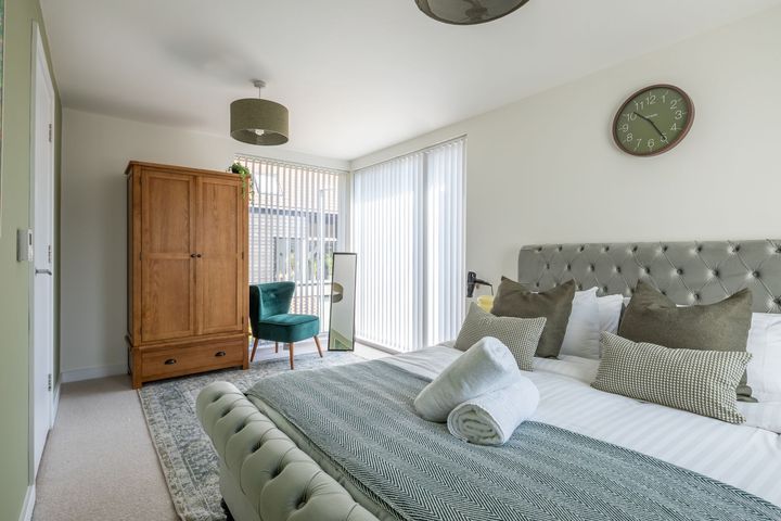 There is a clock on the wall above the bed in the bedroom.