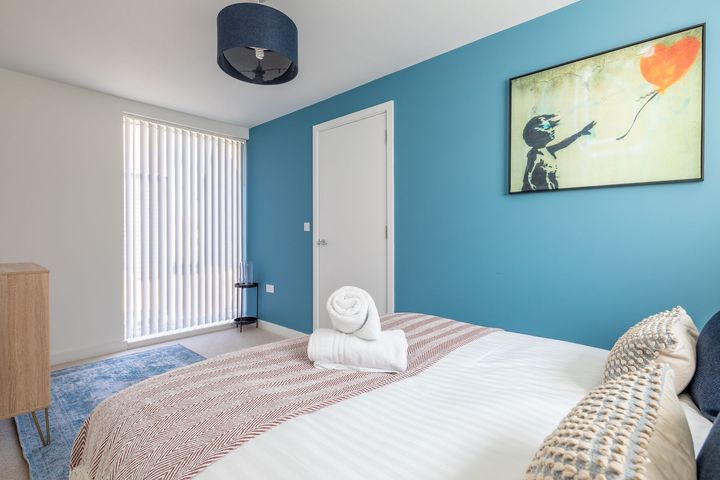 A bedroom with a large bed and a painting on the wall.