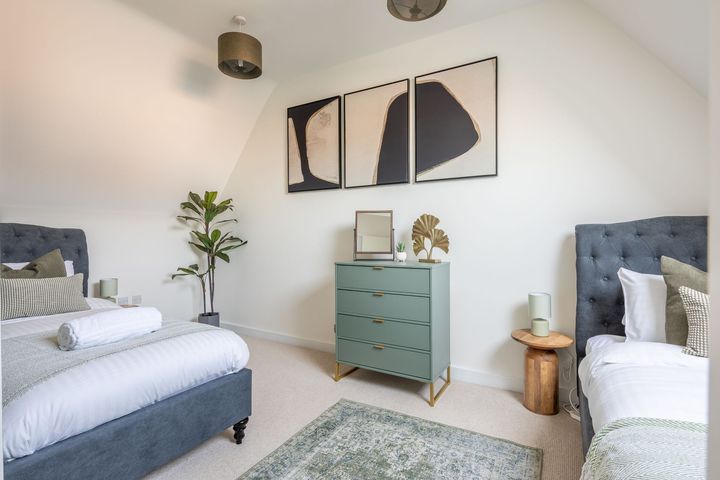 A bedroom with two beds , a dresser and a rug.