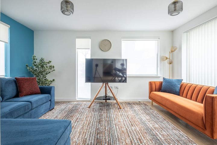 A living room with two couches and a flat screen tv on a stand.