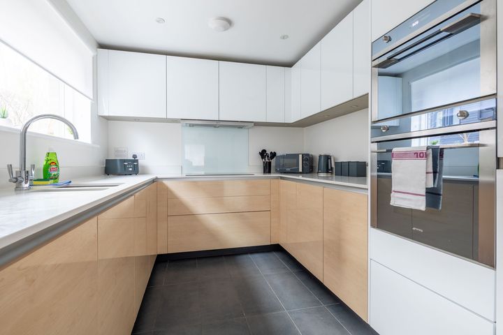 A kitchen with white cabinets , wooden cabinets , stainless steel appliances and a sink.