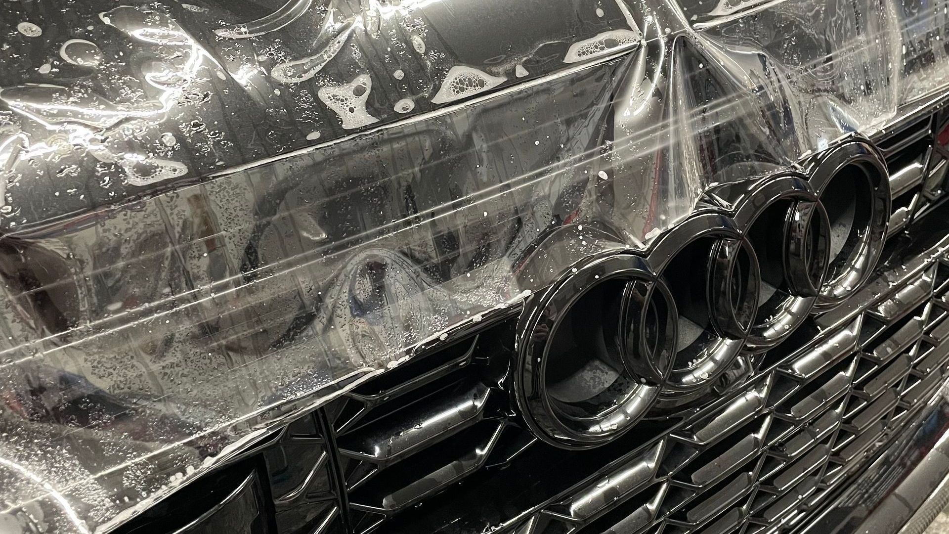 A close up of a black audi car with a clear film on it.