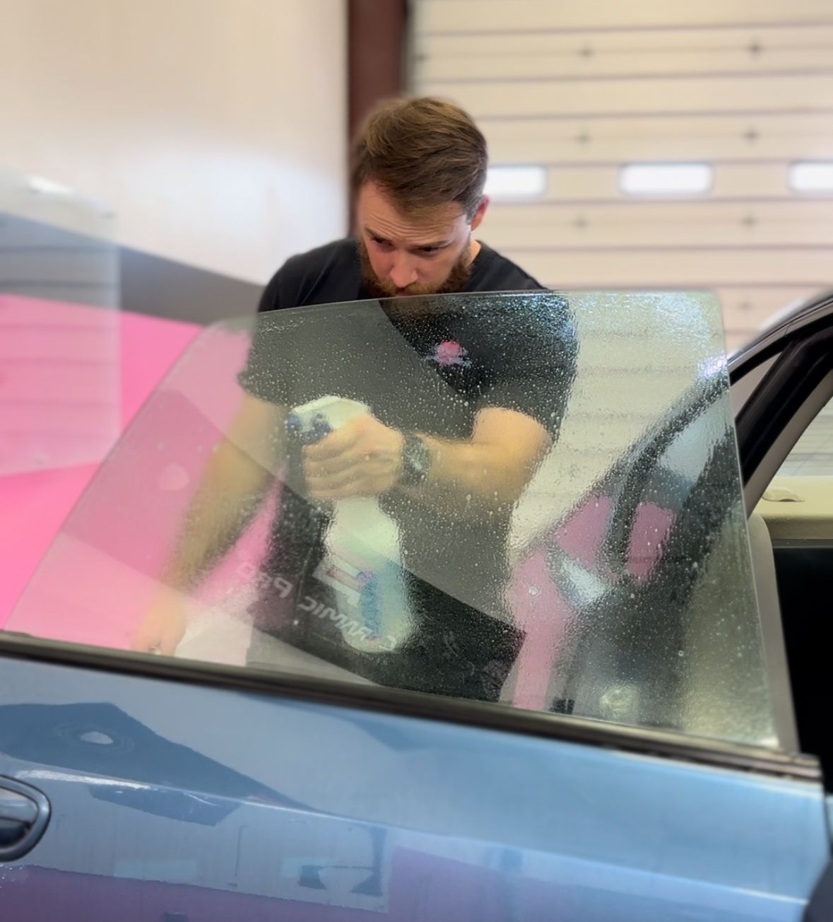 A man spraying a car window with a spray bottle