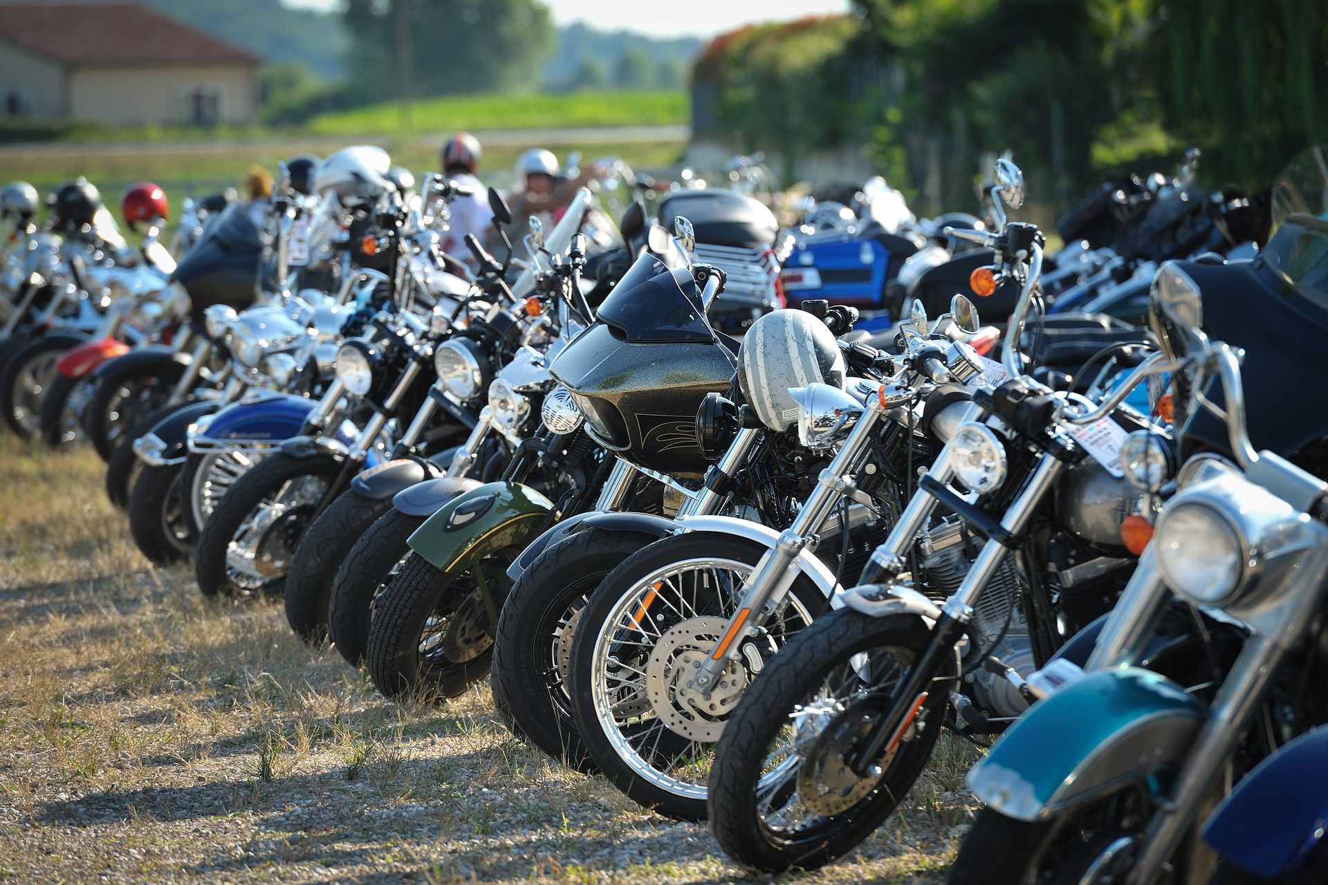 A row of motorcycles are parked in a field.