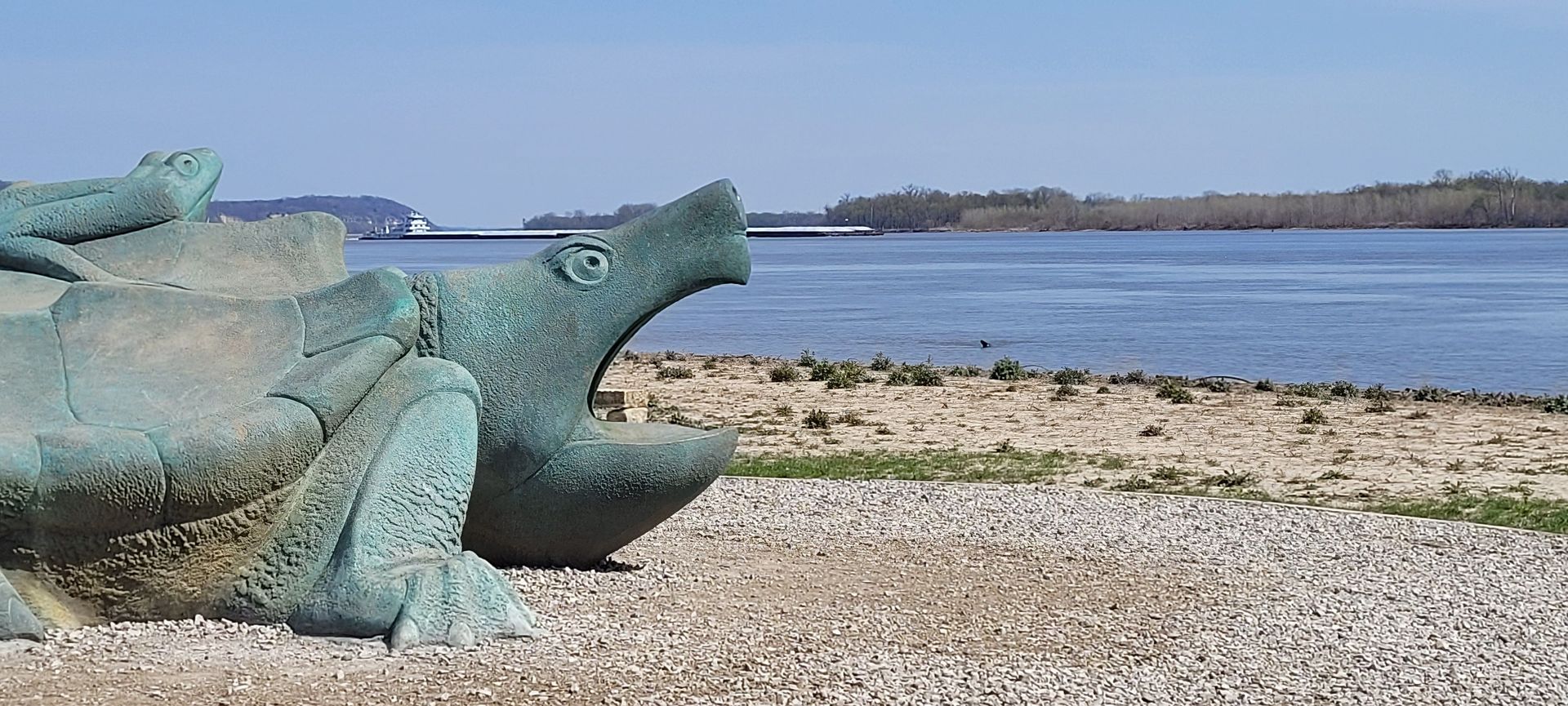 A statue of a dragon is sitting on the beach near the water