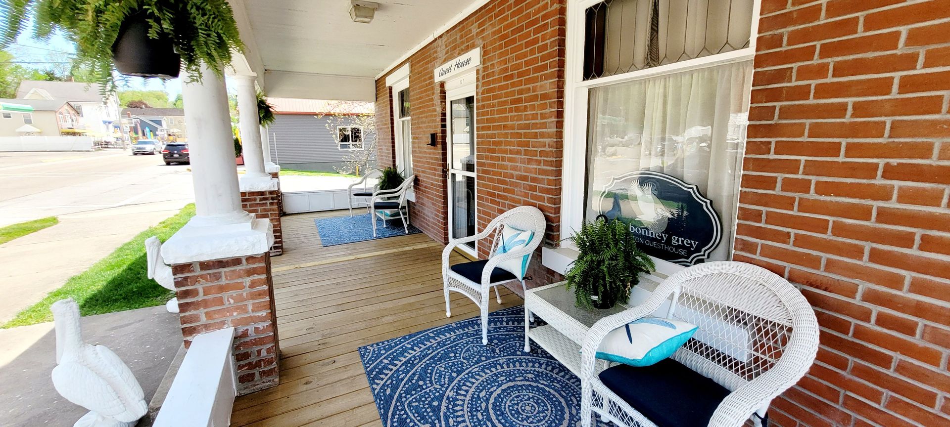 A porch with wicker chairs and a table on a brick house.