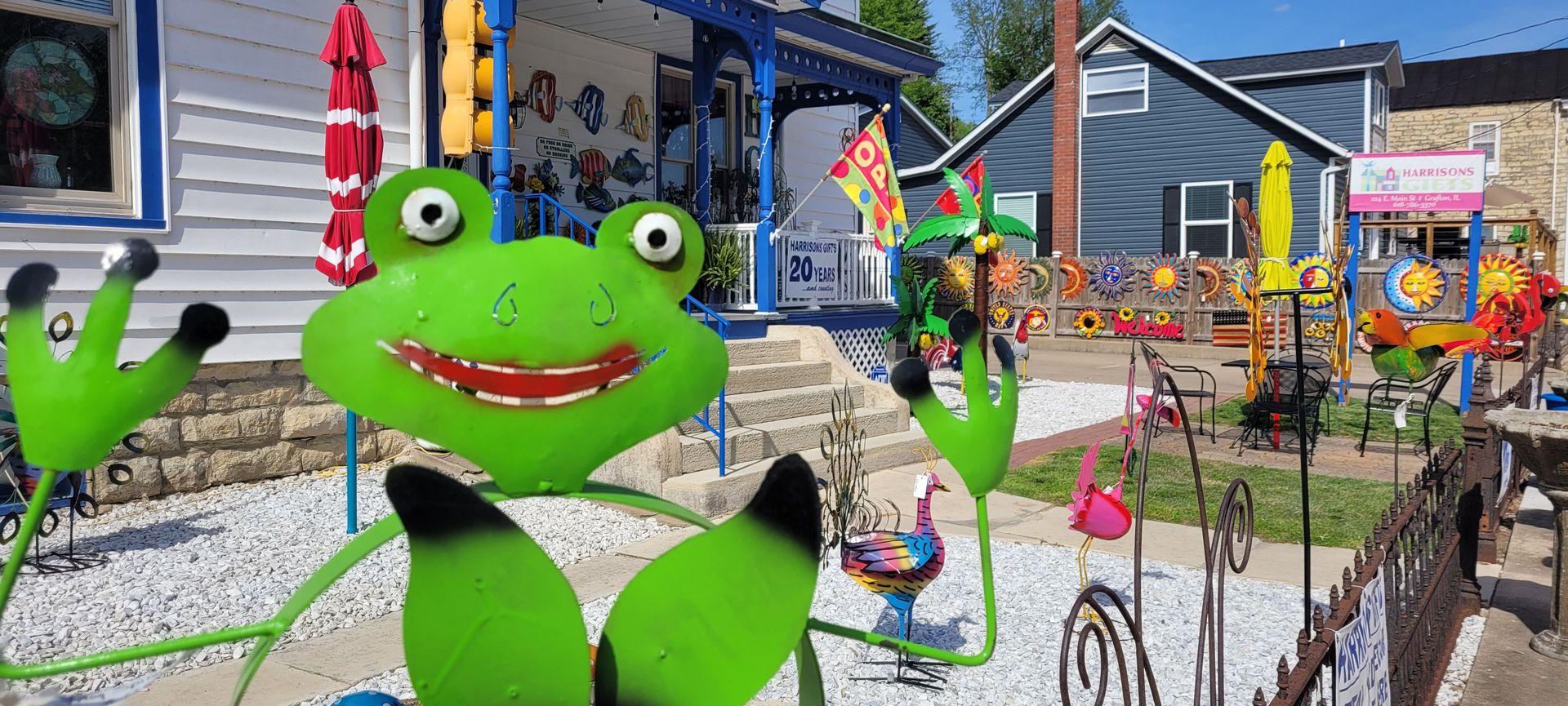 A green frog statue is sitting in front of a house.