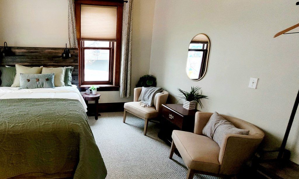 A bedroom with a bed , chair , table and mirror.