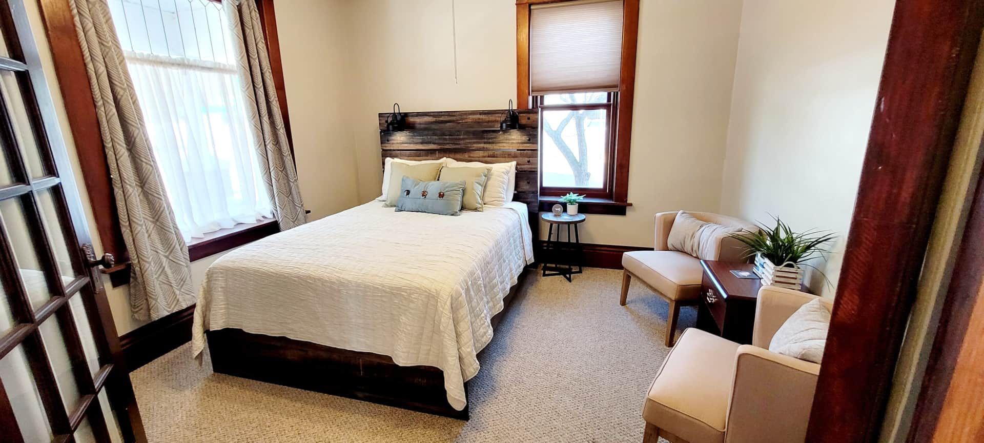 A bedroom with a bed , chair , table and window.