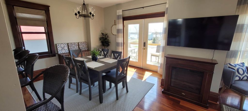 A living room with a dining table , chairs , a fireplace and a flat screen tv.
