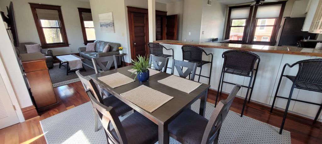 A living room with a dining table and chairs and a bar.