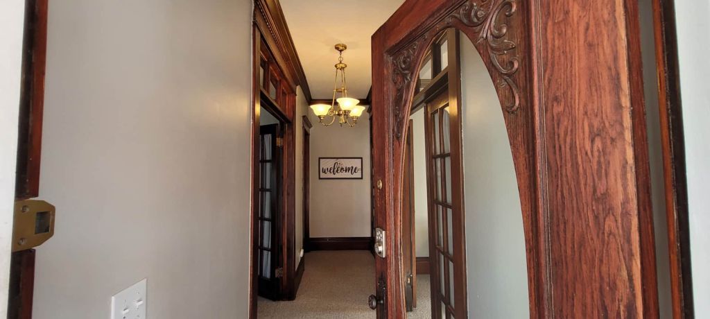 A long hallway with wooden doors and a chandelier hanging from the ceiling.