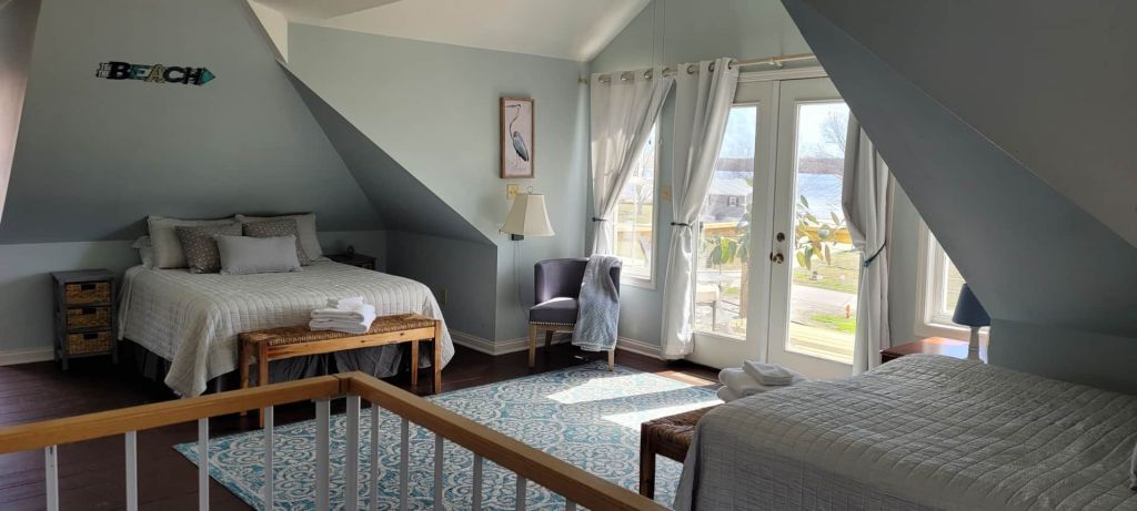 A bedroom with two beds , a chair , and a large window.