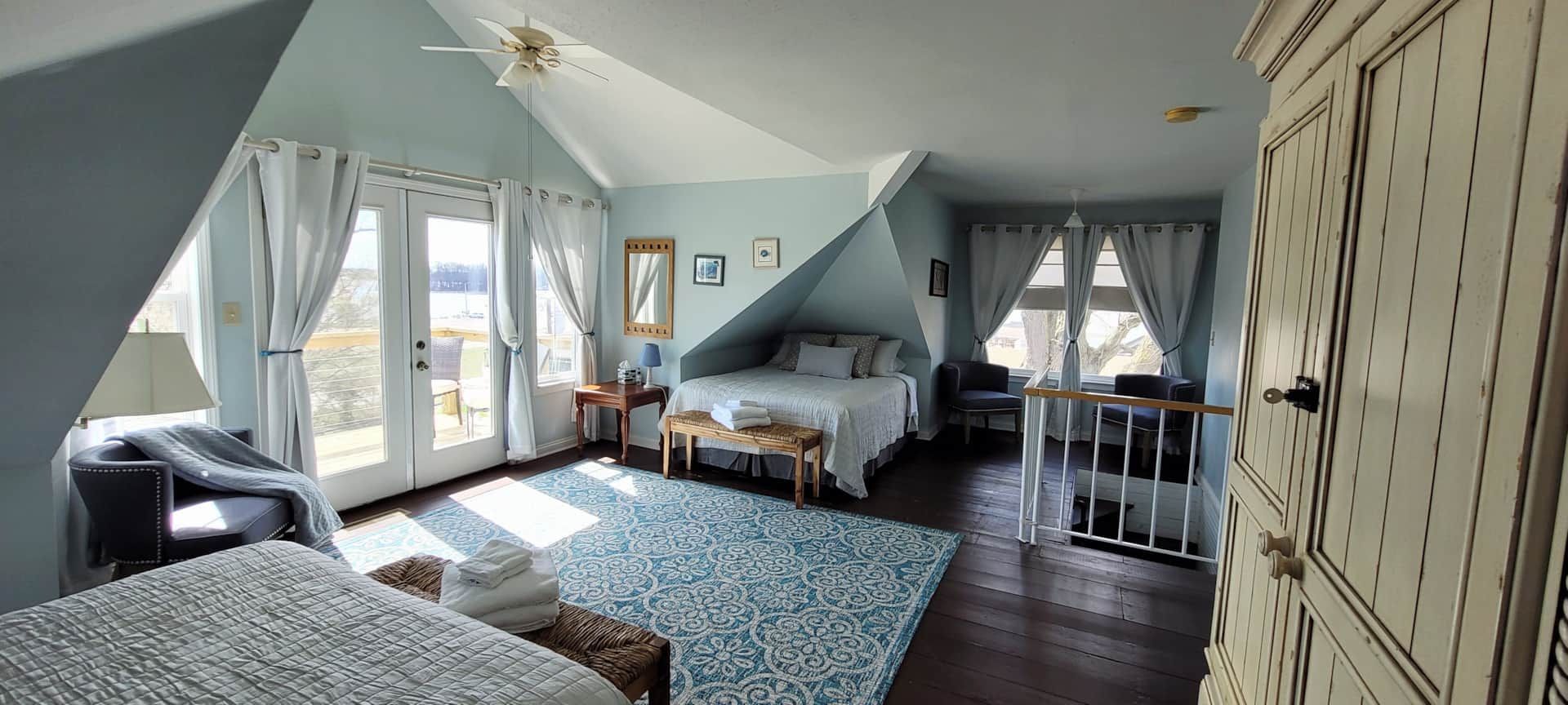 A bedroom with two beds , a rug , a chair , and a staircase.