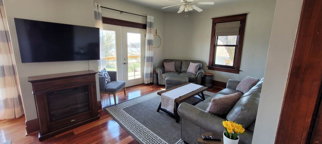 A living room with a couch , fireplace , television and a ceiling fan.