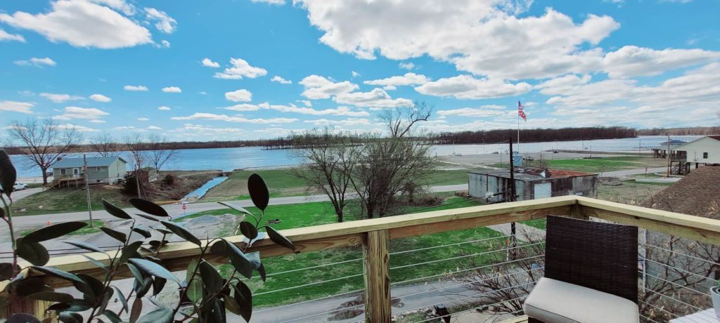A view of a lake from a balcony with a wooden railing.
