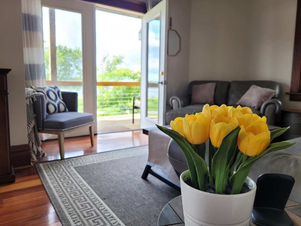 A living room with a couch , chair , table and a vase of yellow flowers.