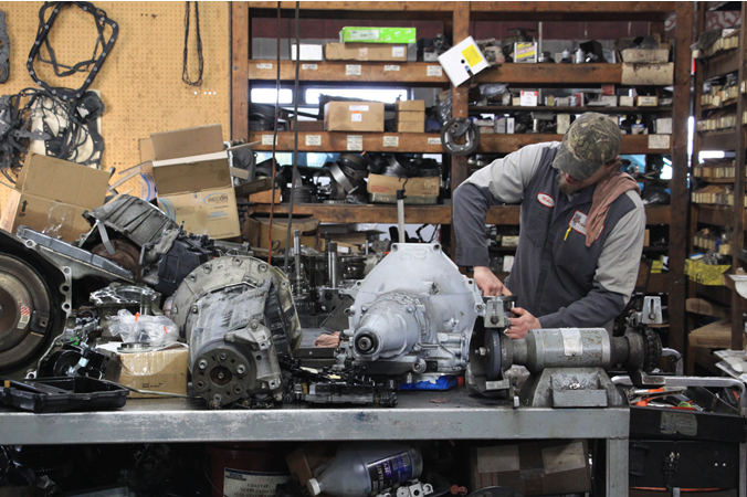 A man is working on a gearbox in a garage.