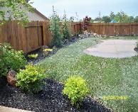 A backyard with a wooden fence and a patio.