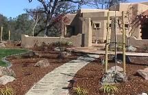 A house with a walkway leading to it and trees in front of it.