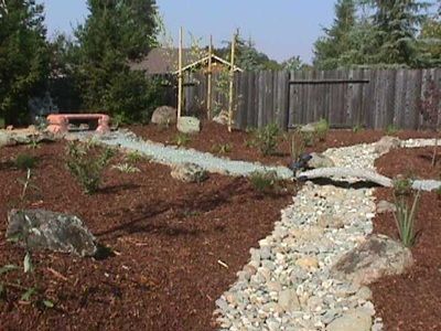 A rocky path in a garden with a wooden fence in the background