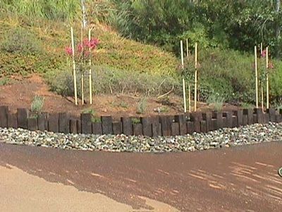 A wooden fence is surrounded by rocks and trees on a hillside.