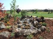 A waterfall is surrounded by rocks and trees in a garden.