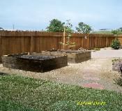 A backyard with a wooden fence and a fire pit.