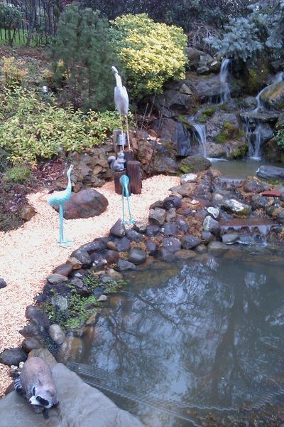 A pond surrounded by rocks and trees with a waterfall in the background