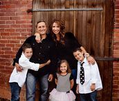 A family is posing for a picture in front of a brick wall.