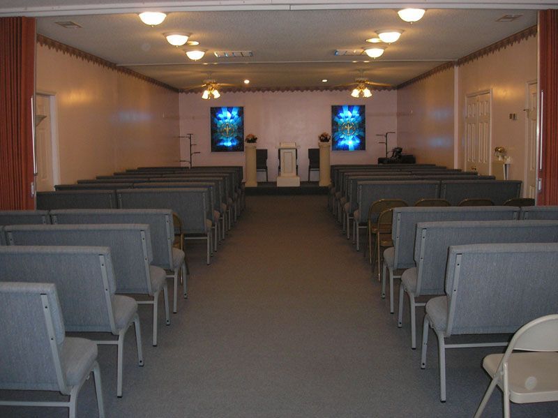Empty chapel with rows of gray benches facing a small altar at the front.