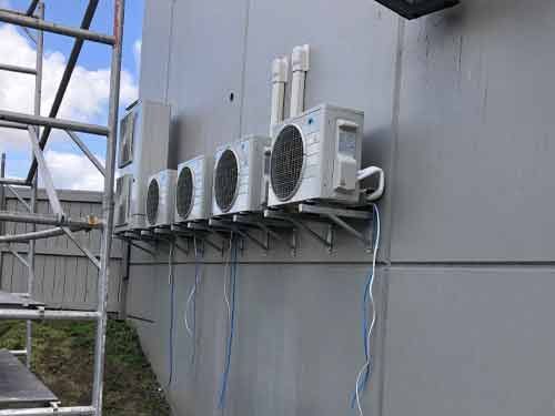 A row of air conditioners mounted on the side of a building.