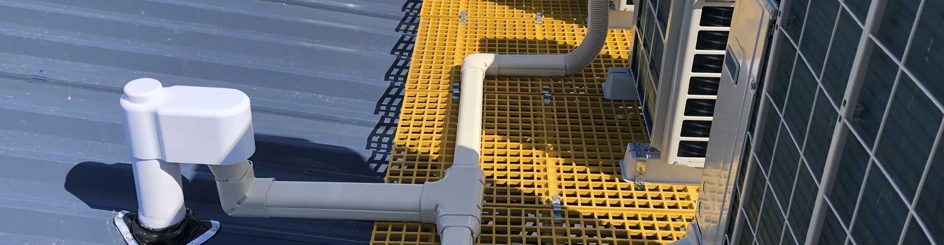 A white toilet is sitting next to a yellow fence. A white toilet is sitting next to a yellow fence.
