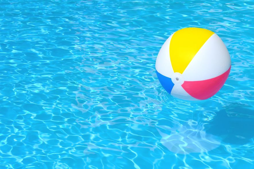 Beach ball floating in a blue swimming pool; yellow, red, blue, and white sections.