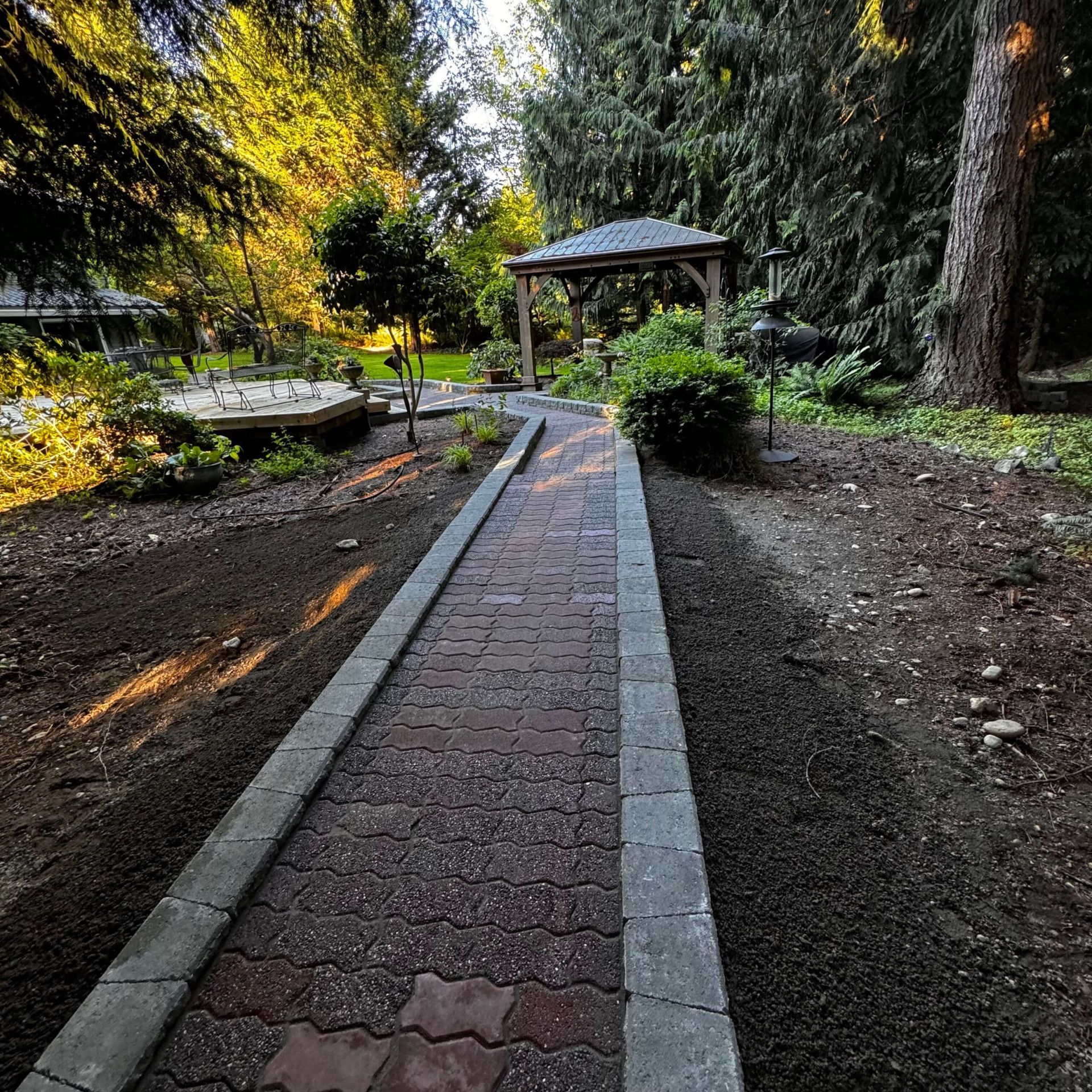 A brick walkway leading to a gazebo in a park.