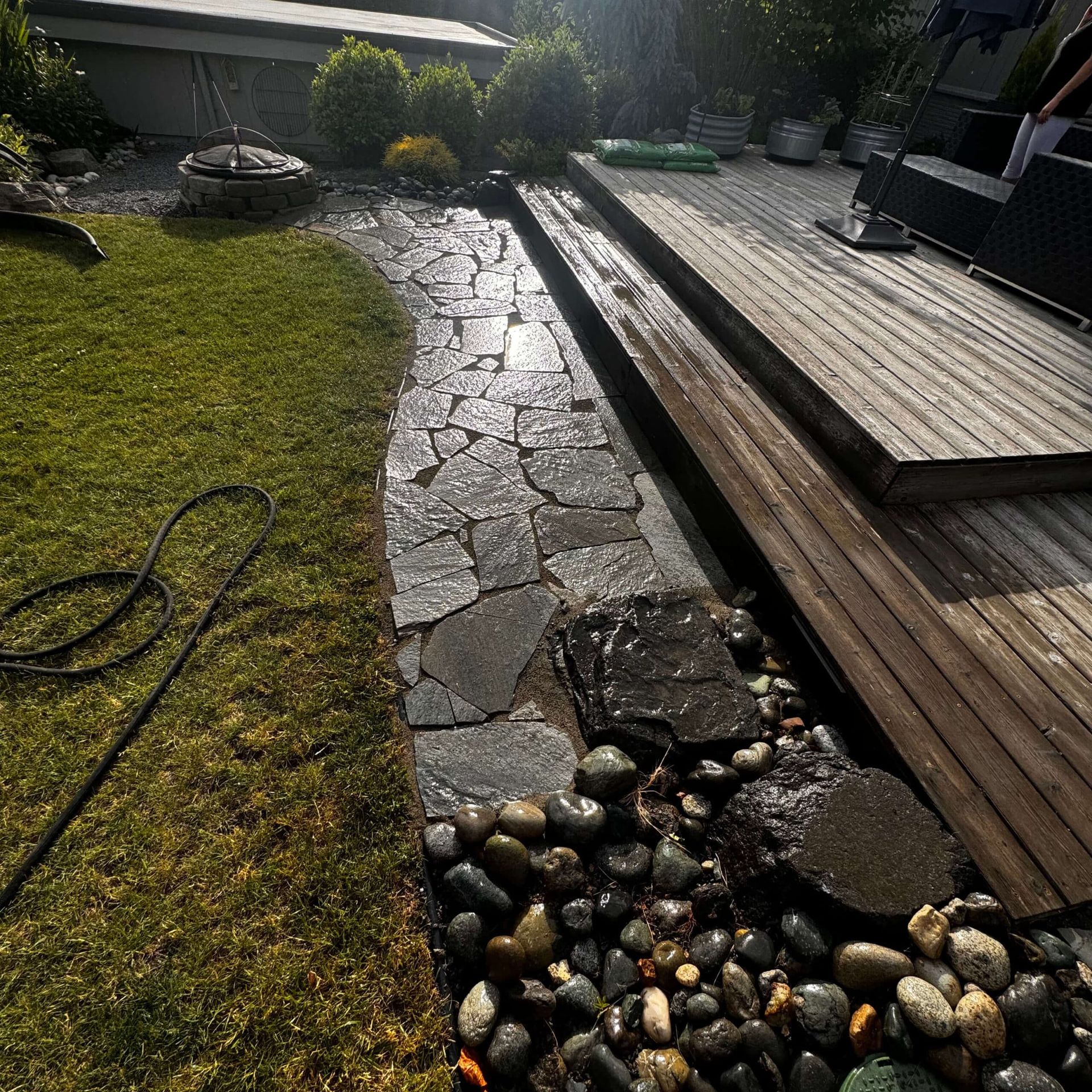 A stone walkway leading to a wooden deck in a backyard
