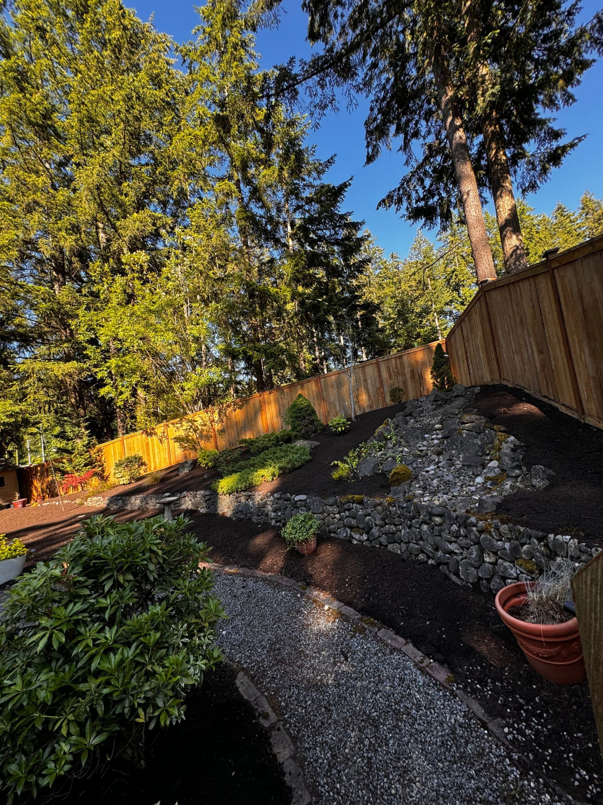 A garden with a wooden fence and trees in the background