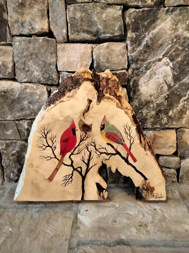 Two cardinals are sitting on a tree branch on a piece of wood.