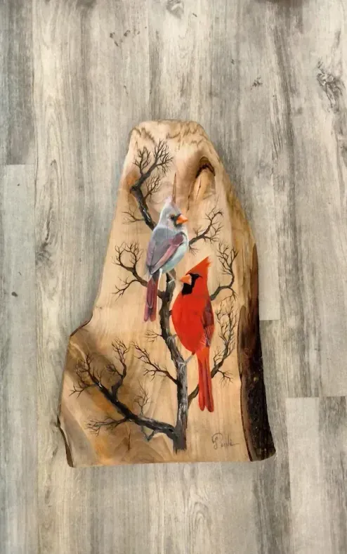 A painting of two cardinals sitting on a tree branch.