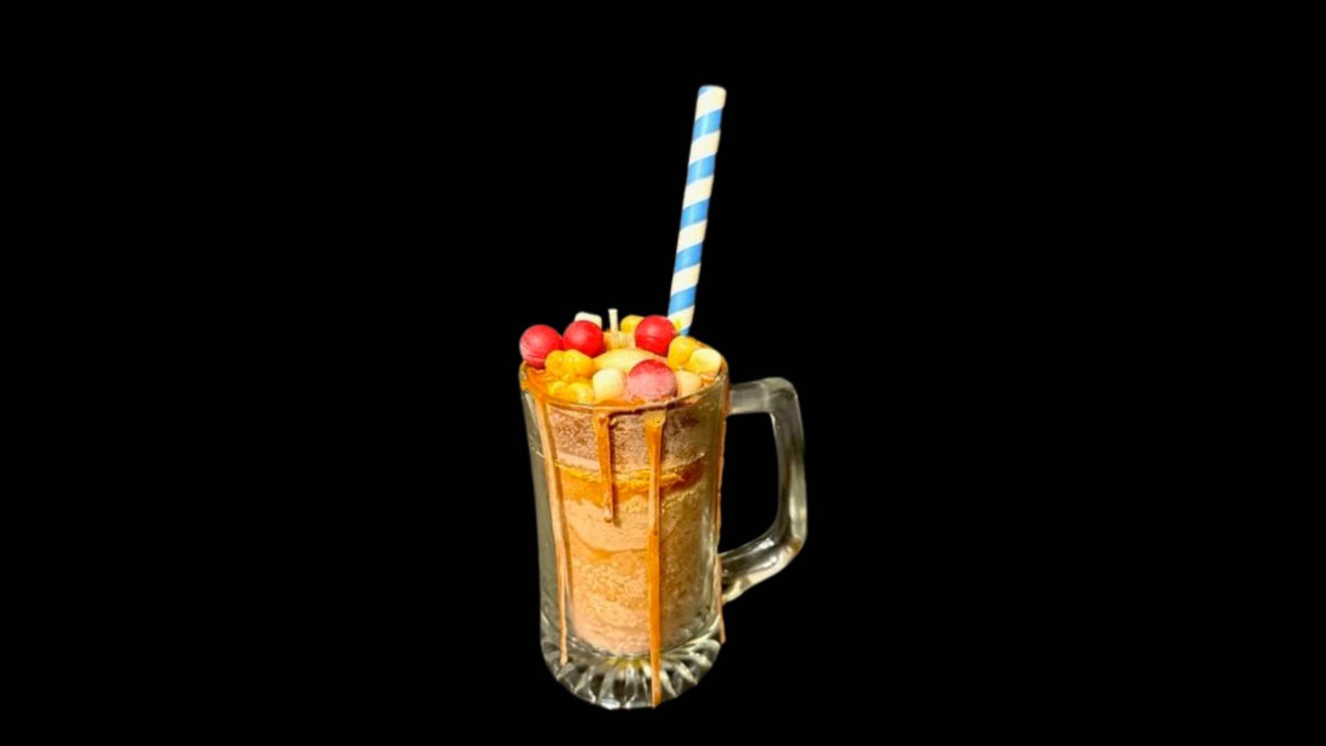 A milkshake with fruit and a straw in a glass on a black background.