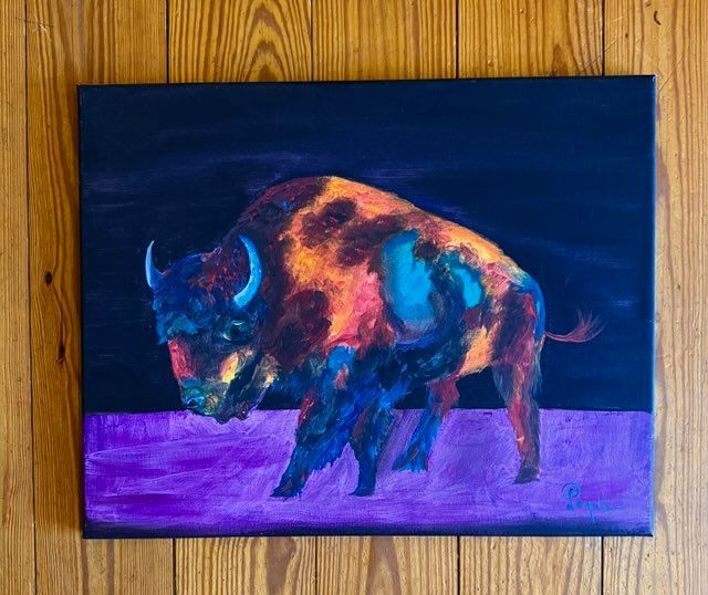 A colorful painting of a bison is hanging on a wooden wall.