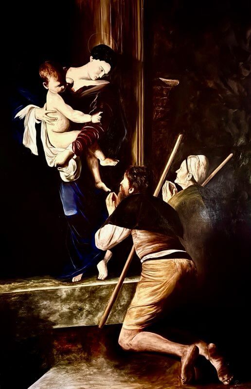 A man is kneeling down in front of a painting of a woman holding a baby.