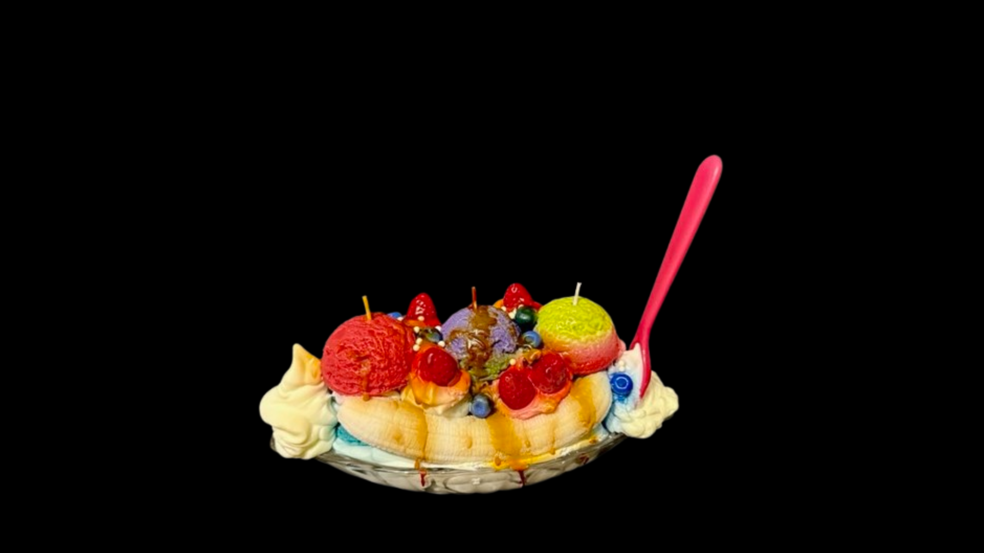 A banana split with candles and a spoon on a black background.
