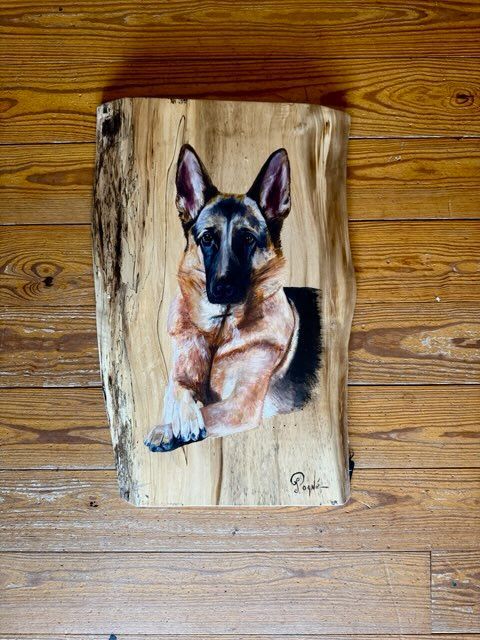 A painting of a german shepherd on a piece of wood on a wooden floor.